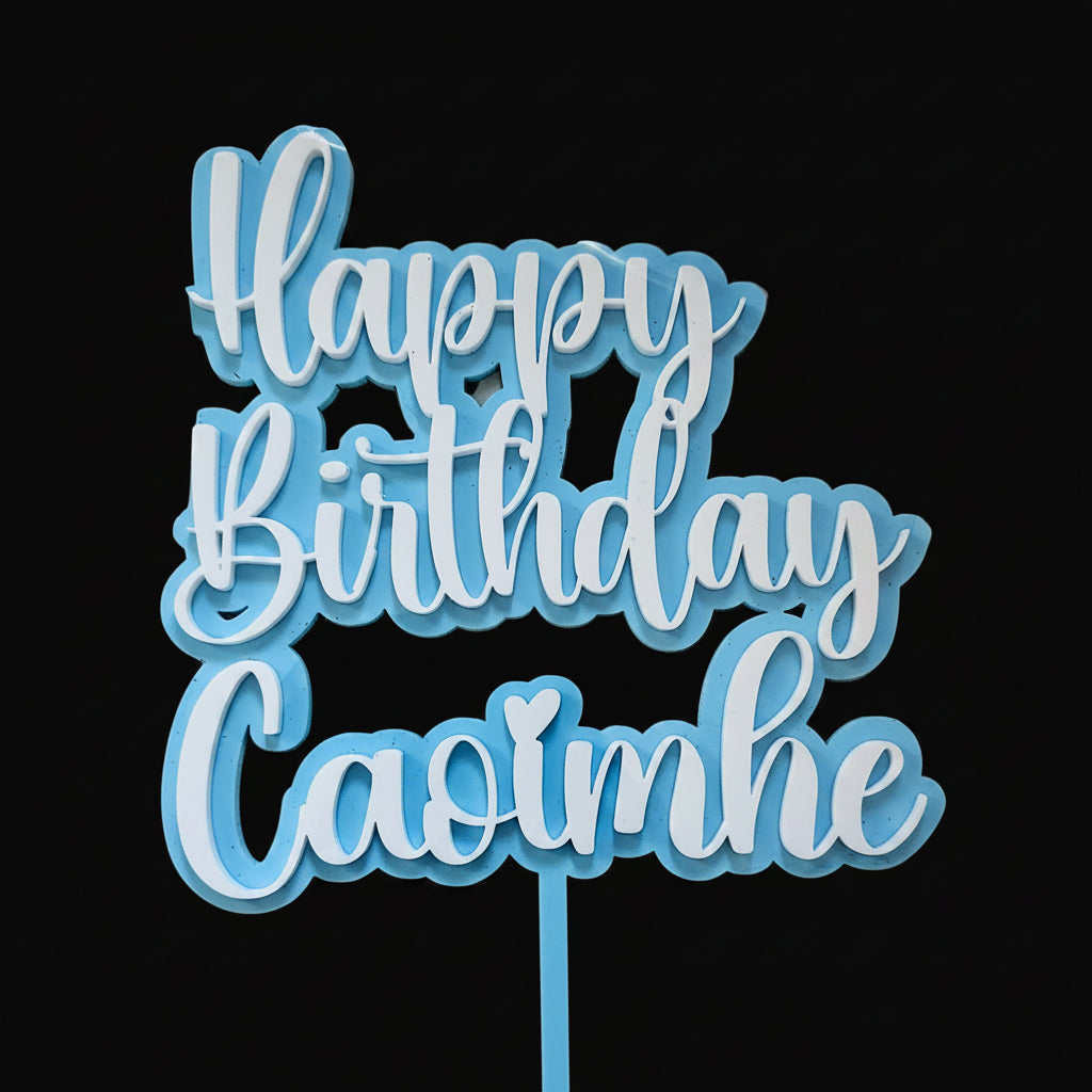 Blue and white 'Happy Birthday Caoimhe' decorative sign on a reflective surface.